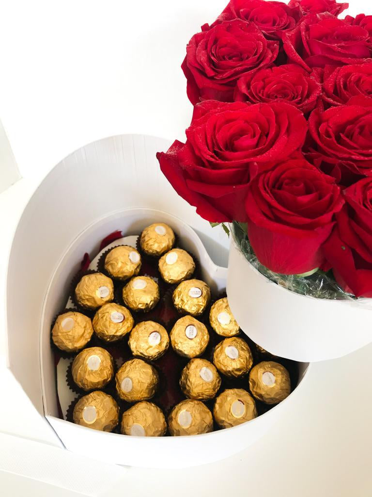 A heart-shaped chocolate box containing red roses and yellow chocolates, presenting a luxurious and romantic gift.