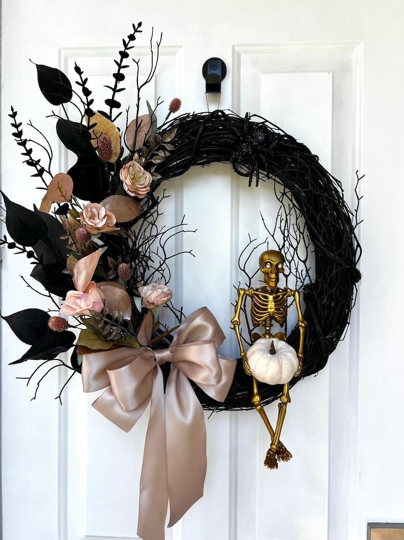 Halloween wreath with skeleton, pumpkin, and decorative elements on a white door.
