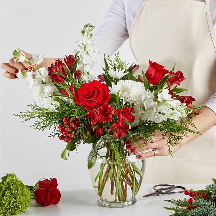 Florist designing a winter flower arrangement  with red and white roses