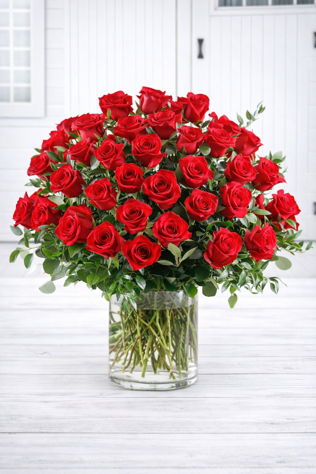 Bouquet of red roses in a clear vase on a white wooden surface