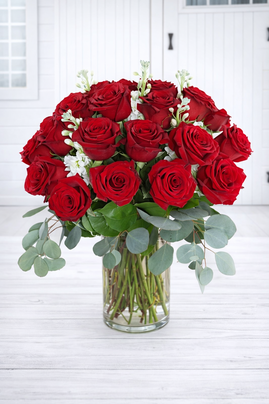 Bouquet of red roses in a clear vase on a white wooden surface