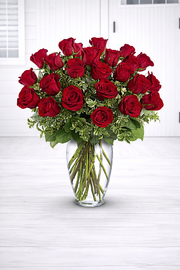 Bouquet of red roses in a clear vase on a white surface