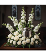 White memorial urn flower arrangement with roses, snapdragons and carnations surrounding a cremation urn for funeral or memorial service McKinney TX