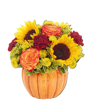 Pumpkin-shaped vase with autumn-themed flowers including sunflowers and roses on a white background