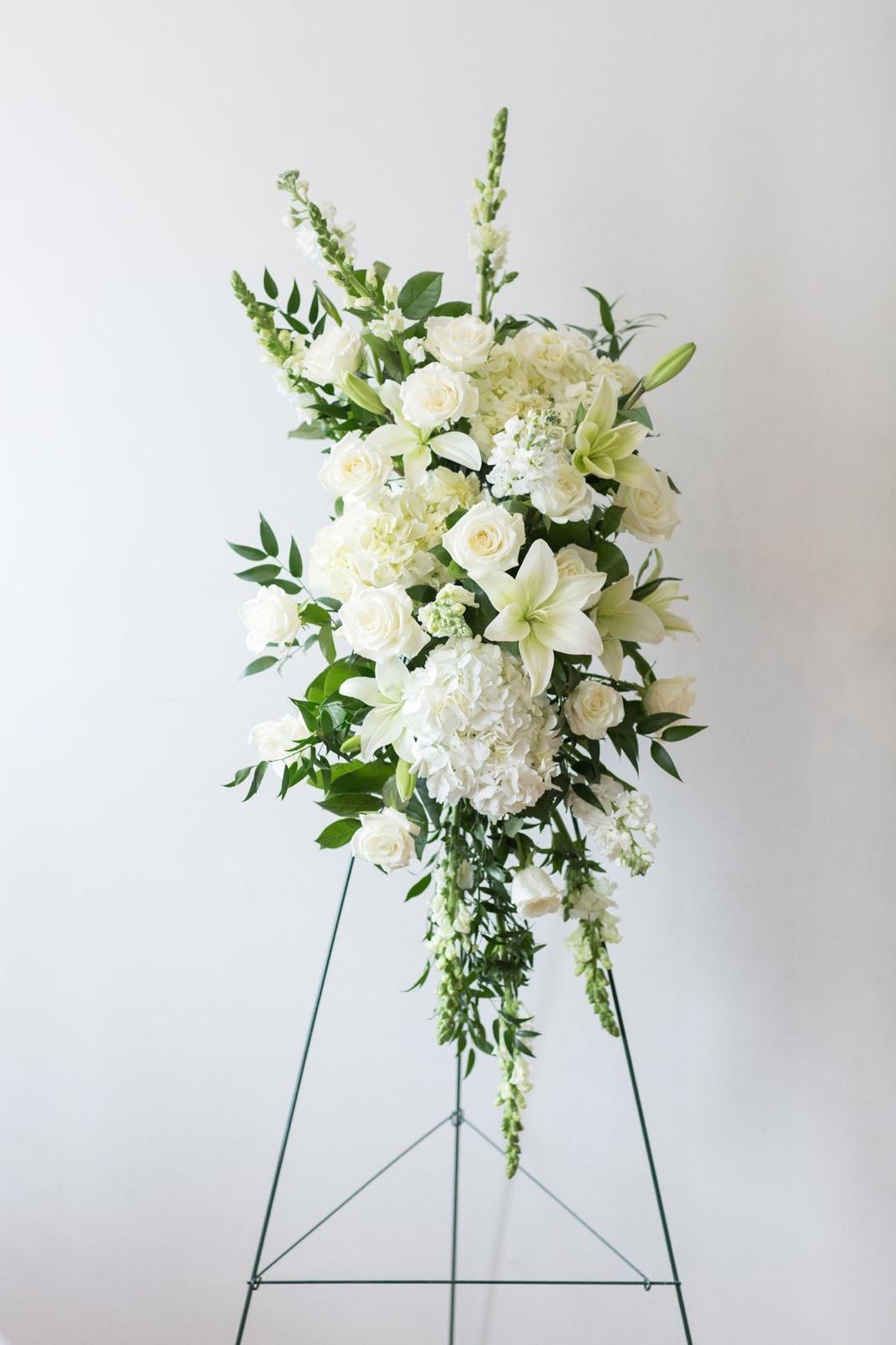 Elegant white standing funeral spray with roses, lilies and hydrangeas on easel – sympathy flowers for funeral service in McKinney Texas